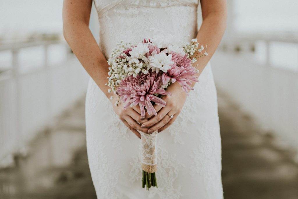 Brides' hands holding Publix bouquet with pink, purple, and white flowers