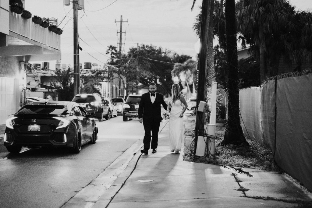 Black and white photo of bride and groom walking Downtown Stuart streets