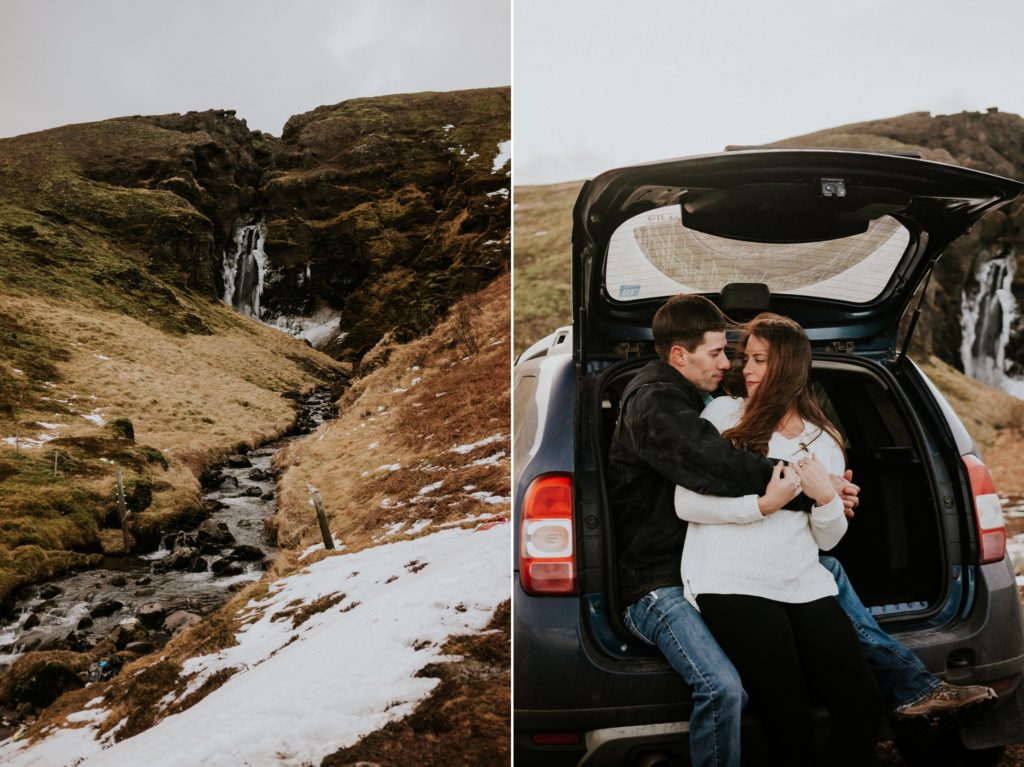 Couple hold each other in back of a van next to waterfall in Iceland elopement road trip