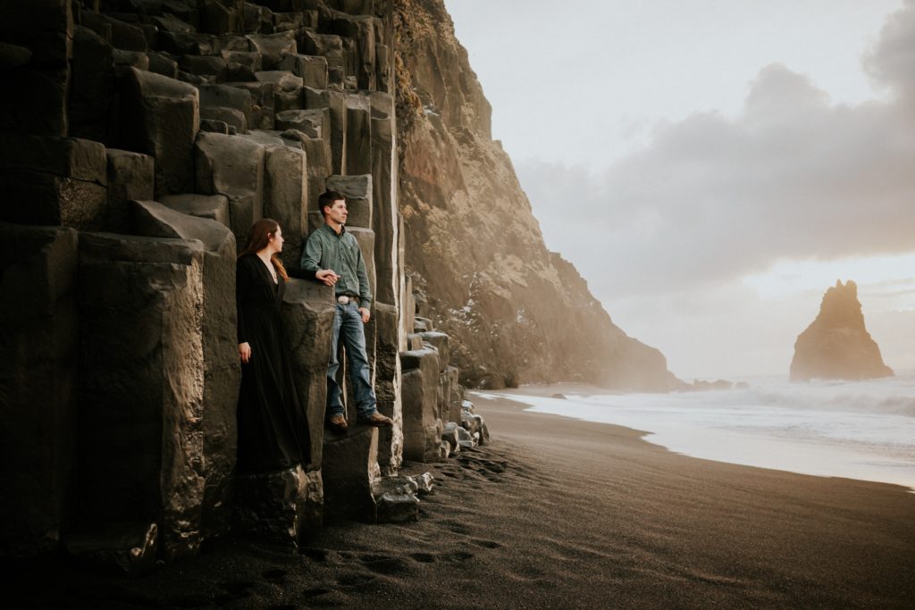Iceland elopement couple stand on basalt columns at sunrise on Reynisfjara Black Sand Beach Vík