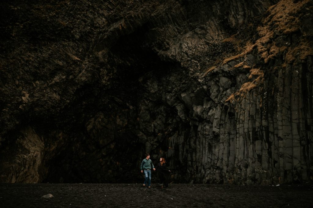 Iceland elopement couple run in front of cave and basalt columns on Reynisfjara Black Sand Beach Vík