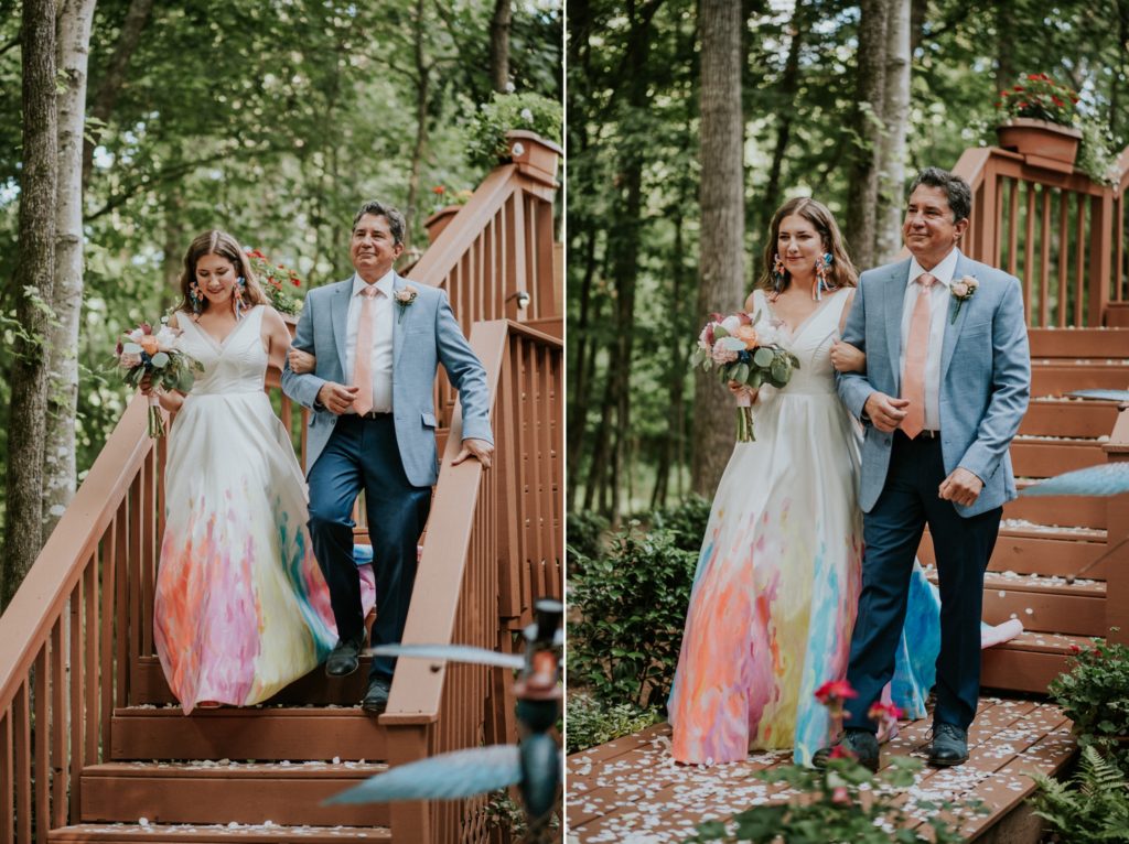 Bride in hand-painted colorful wedding dress walks down aisle with dad woodsy backyard Atlanta GA wedding
