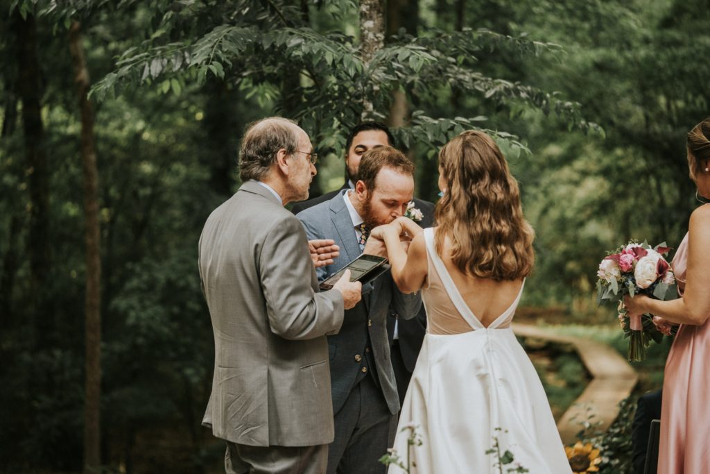 Groom kisses brides hands in Duluth GA wedding ceremony