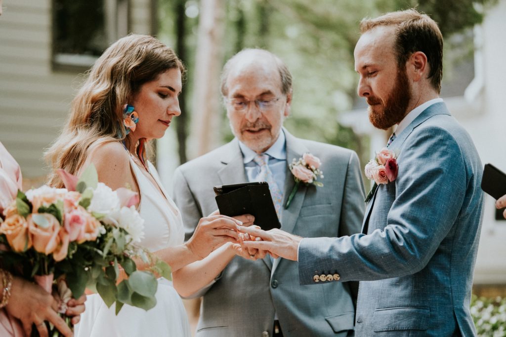 Bride puts ring on grooms finger during wedding ceremony Duluth GA