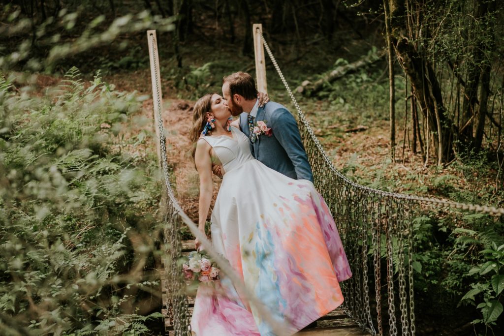 Dip kiss on bridge Atlanta GA backyard wedding with hand-painted dress