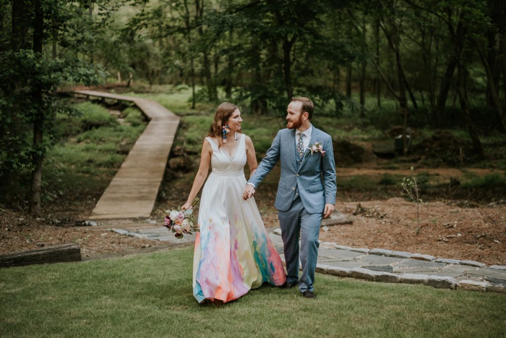 Bride and groom walk in backyard Atlanta GA hand-painted wedding dress