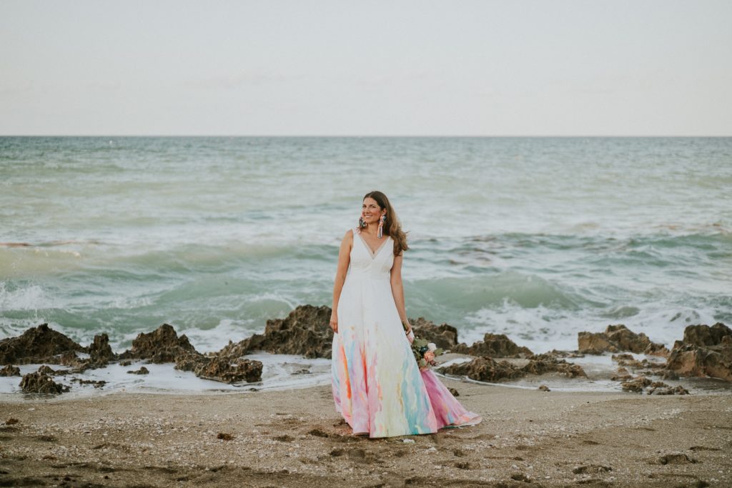 Bride in hand-painted rainbow wedding dress walks on House of Refuge beach Stuart FL elopement Photographer