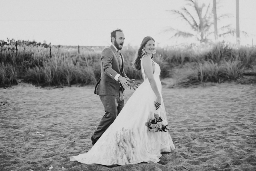 Groom scares bride during beach wedding portrait black and white