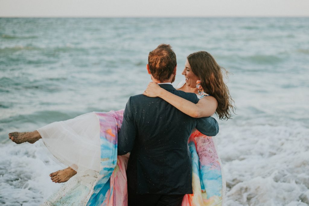 Groom picks up bride in ocean waves House of Refuge beach wedding Stuart Florida elopement photography