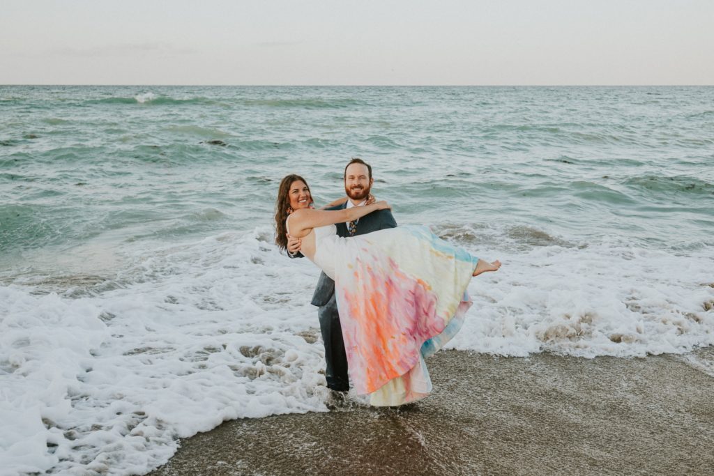 Groom picks up bride in ocean waves House of Refuge beach wedding Stuart Florida elopement photographer