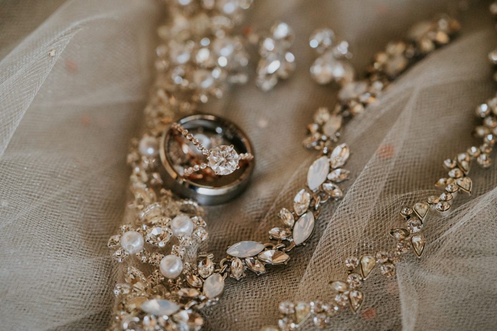 Macro engagement ring and pearl wedding jewelry on rhinestone veil