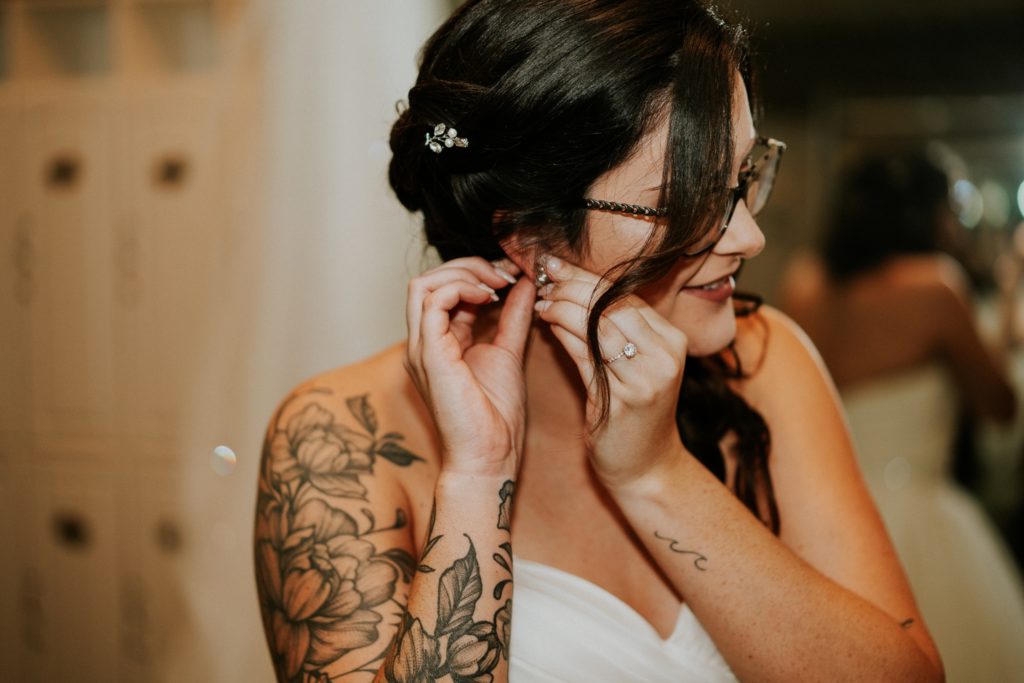 Tattooed bride puts on wedding earrings