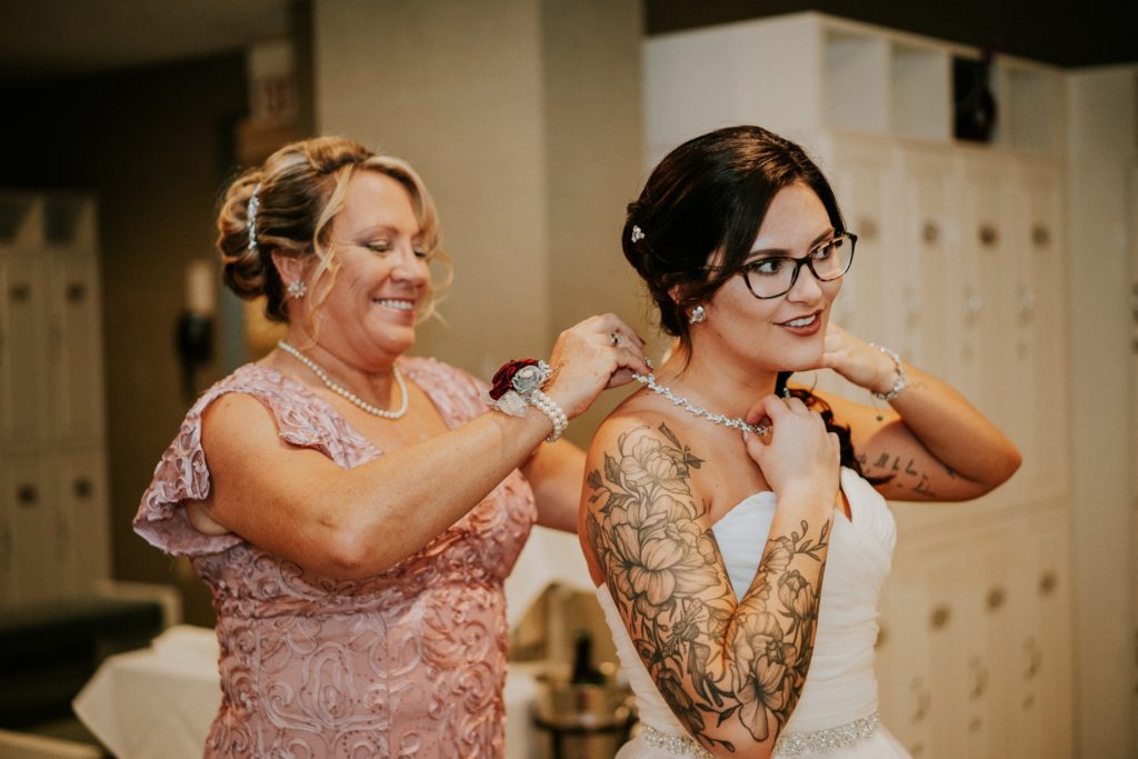 Mom puts wedding necklace on bride