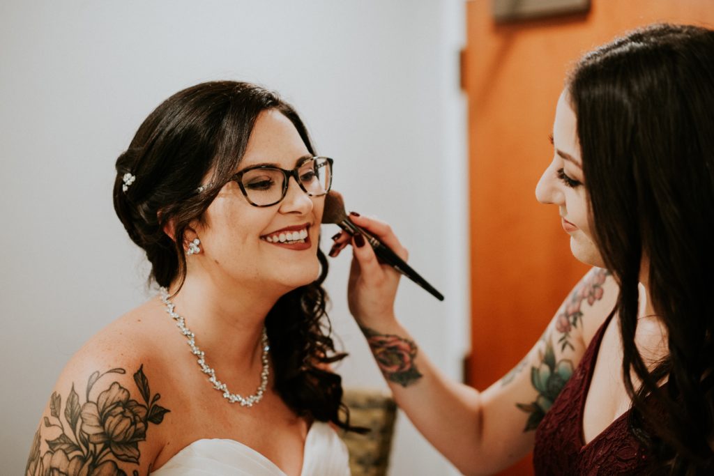 Bridesmaid helps bride with makeup