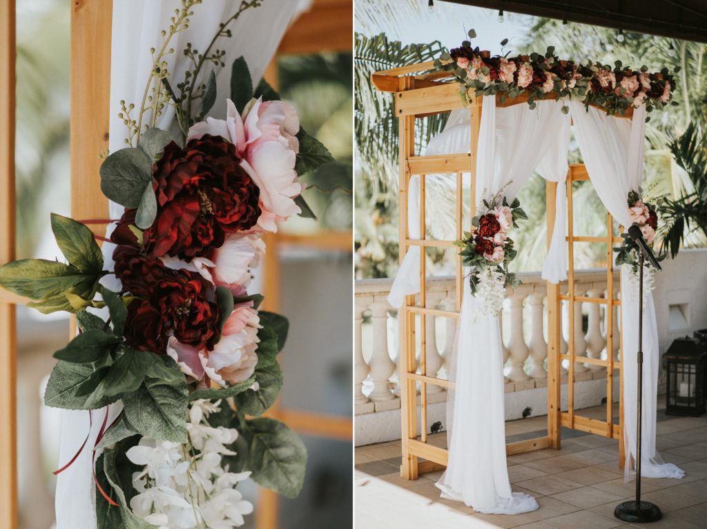 Wood wedding arch arbor with red and pink flowers and white drapes ceremony decor