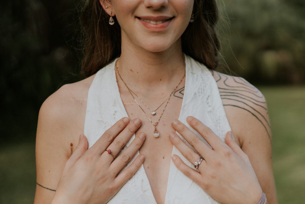 Bri holds hands to chest to show off all her wedding jewelry details