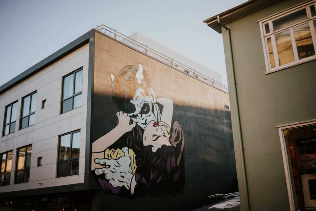 Monster holding woman mural street art on side of house in Reykjavík Iceland