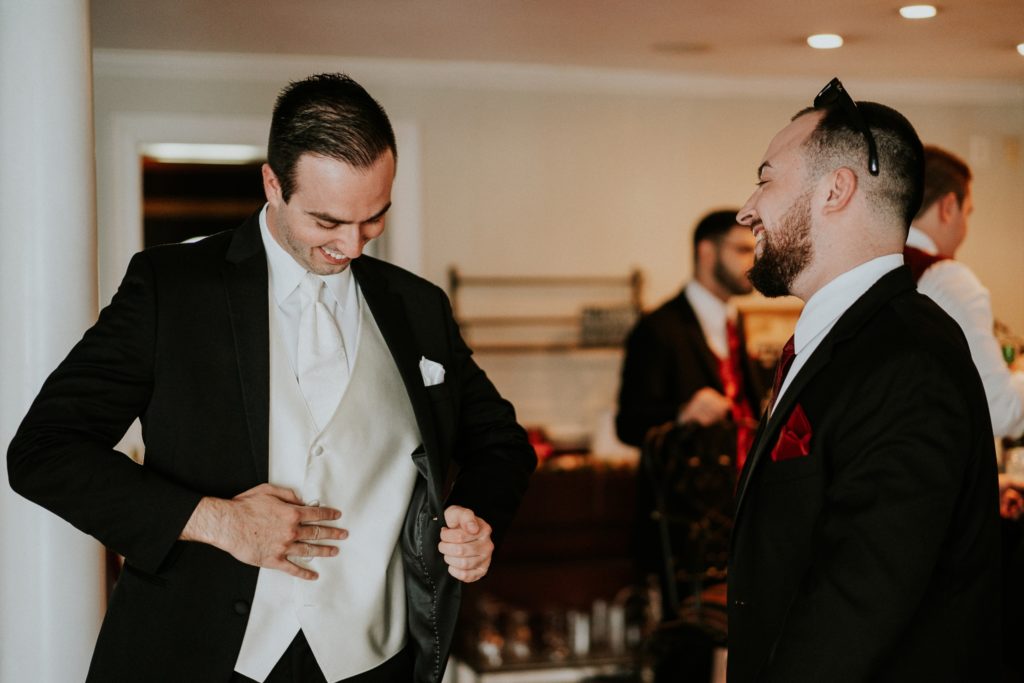 Groomsmen helps groom put on jacket