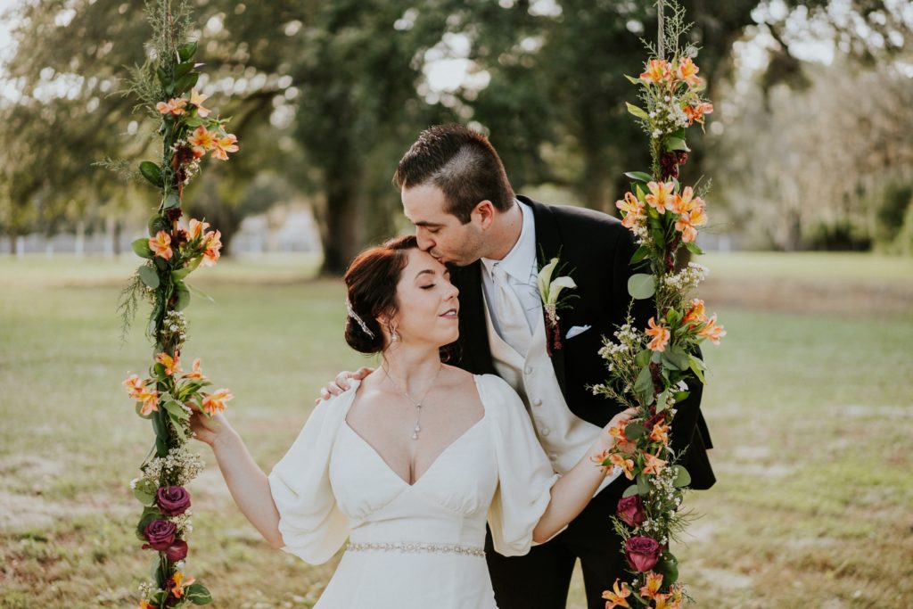 Casa Lantana wedding flower swing groom kisses bride on forehead