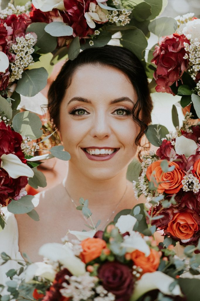 Bridesmaid bouquets of red and orange roses surround vintage bride face Casa Lantana Brandon FL wedding