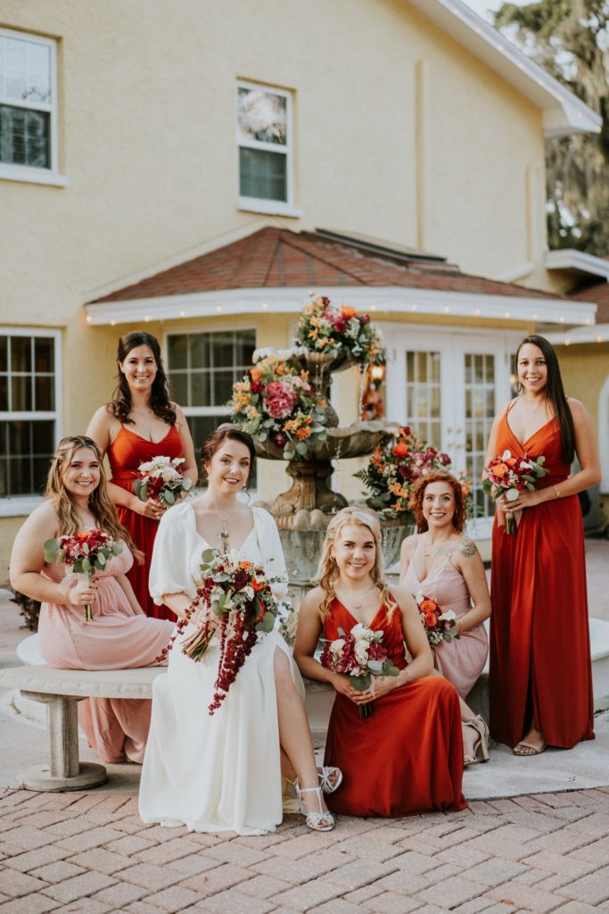 Casa Lantana wedding fountain with flowers with sitting bride and bridesmaids in rust orange and blush pink dresses