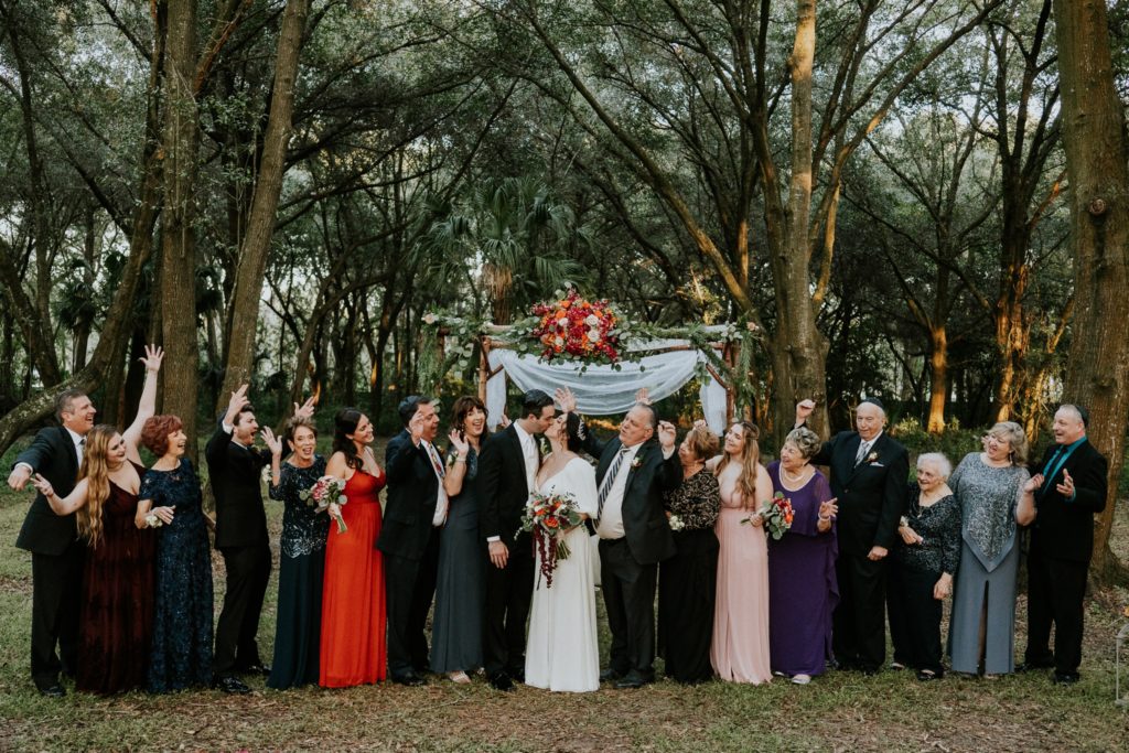 Family members cheer for kissing couple in front of chuppah in woodsy wedding Casa Lantana Brandon FL