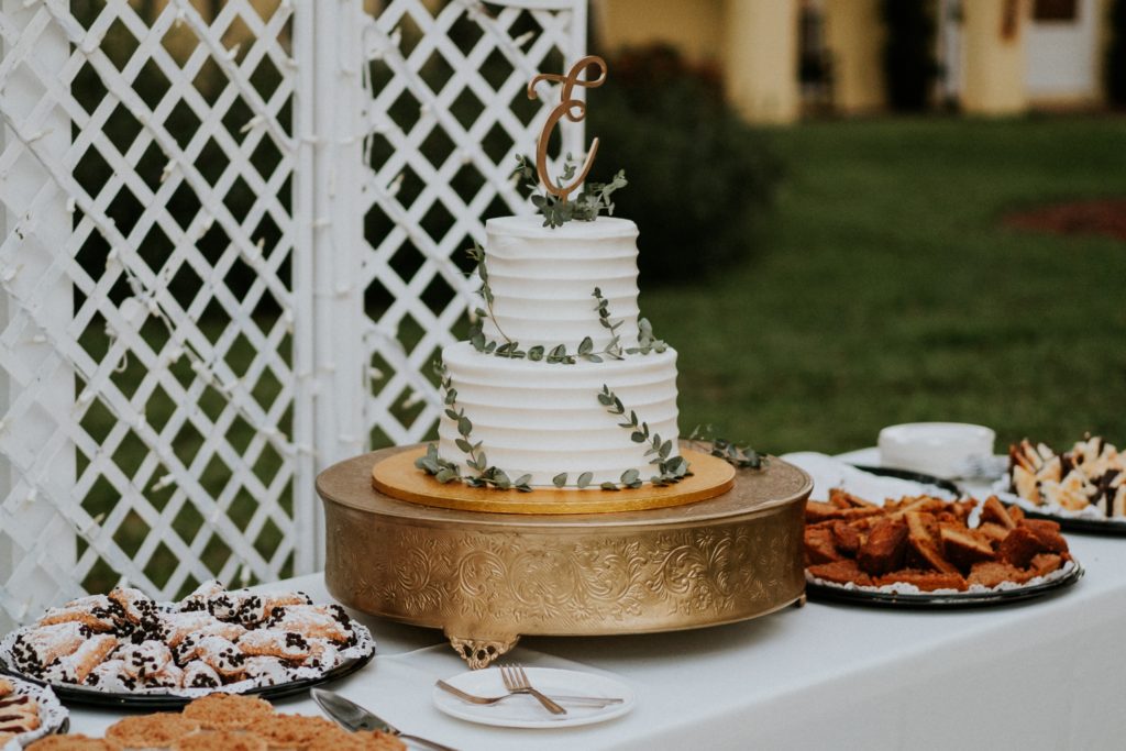 White wedding cake with greenery on dessert table