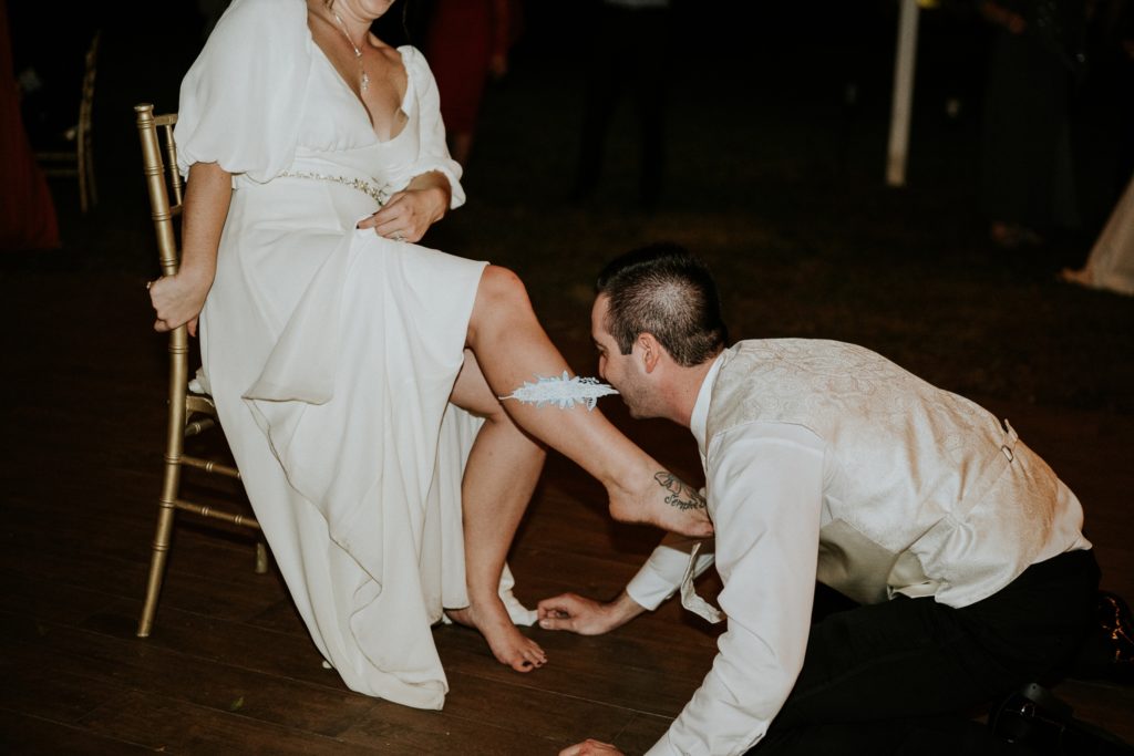 Groom pulls garter down bride's leg with teeth