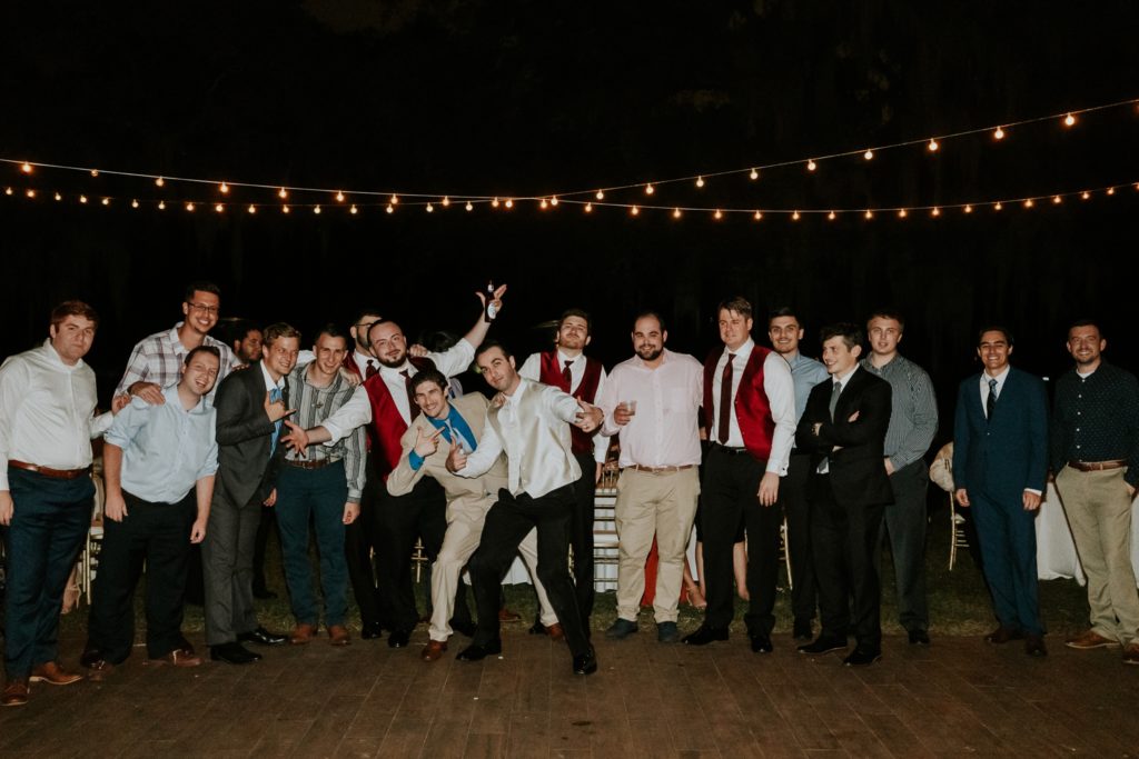 Groom poses with wedding guests for garter toss
