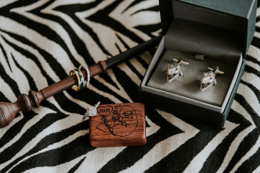 Harry Potter theme wedding details with rings on wand, niffler ring box with Mia Donna engagement ring, and T-rex silver cufflinks