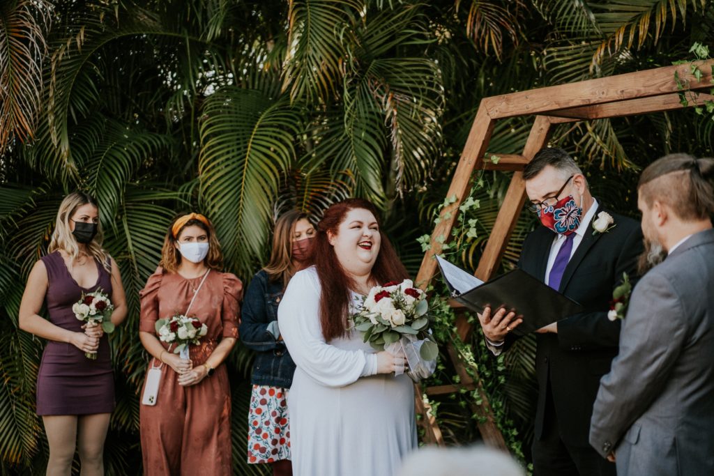Bride laughs during officiant speech in backyard wedding ceremony