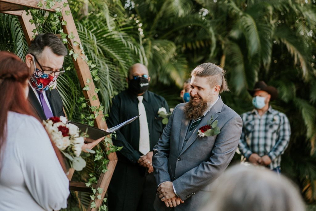 Groom laughs during officiant speech in backyard wedding ceremony