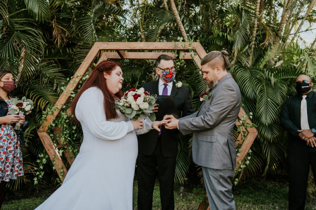 Bride and groom exchange rings at backyard wedding ceremony
