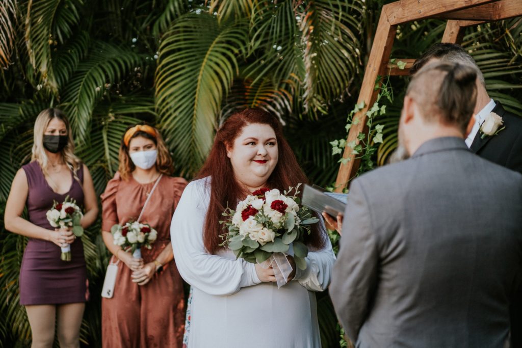 Bride smiles at groom during vows in backyard wedding ceremony