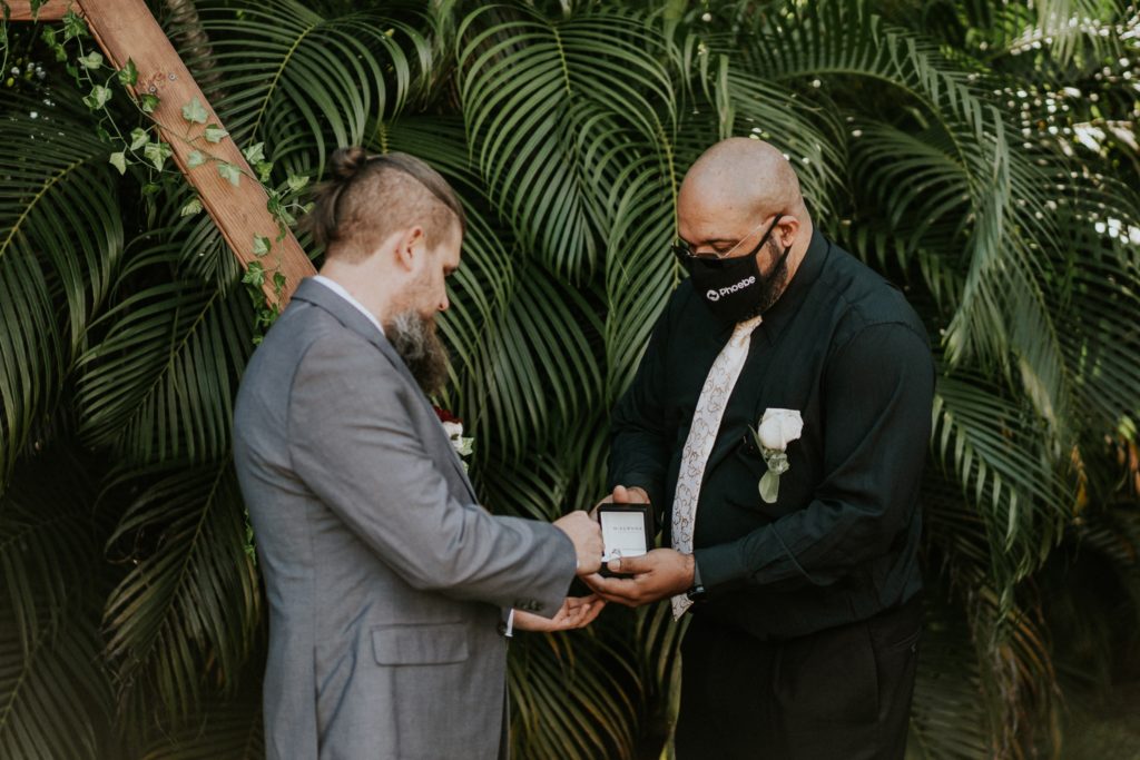 Best man gives groom the rings in backyard wedding ceremony