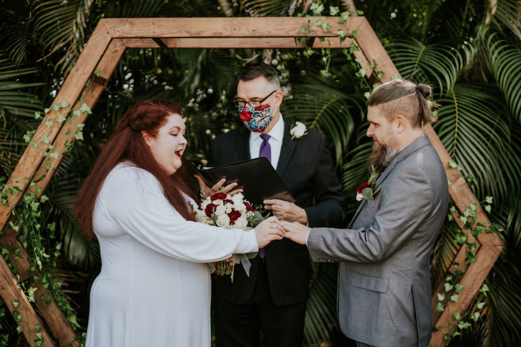 Bride and groom exchange rings at backyard wedding ceremony