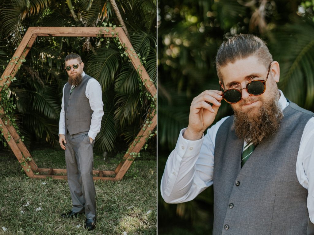 Cool groom in sunglasses wearing Men's Wearhouse suit and Slytherin tie in front of geometric hexagon arch West Palm Beach FL backyard wedding