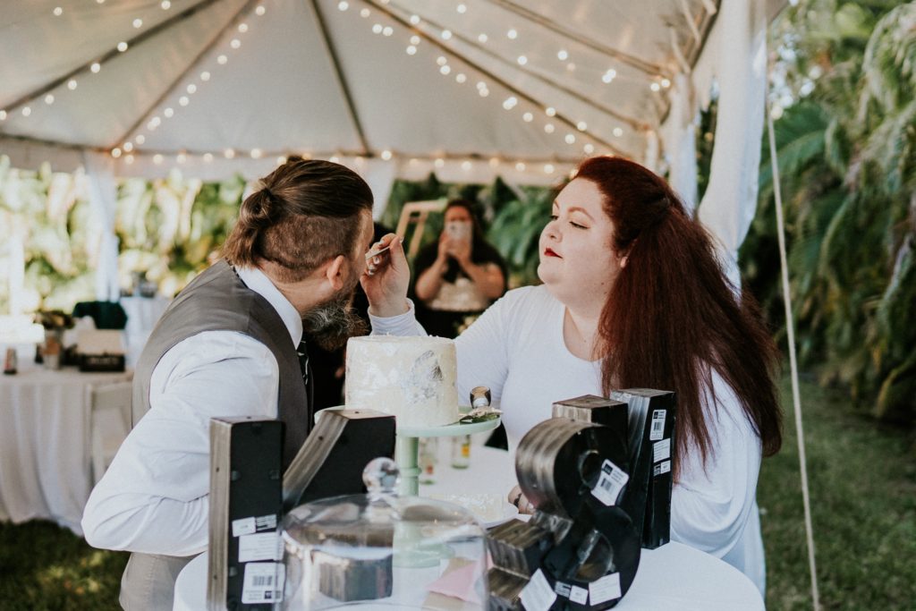Bride feeds groom in backyard wedding cake cutting