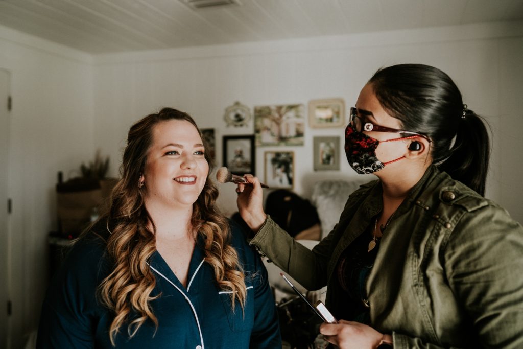 Makeup artist applies blush to bride ini bridal suite