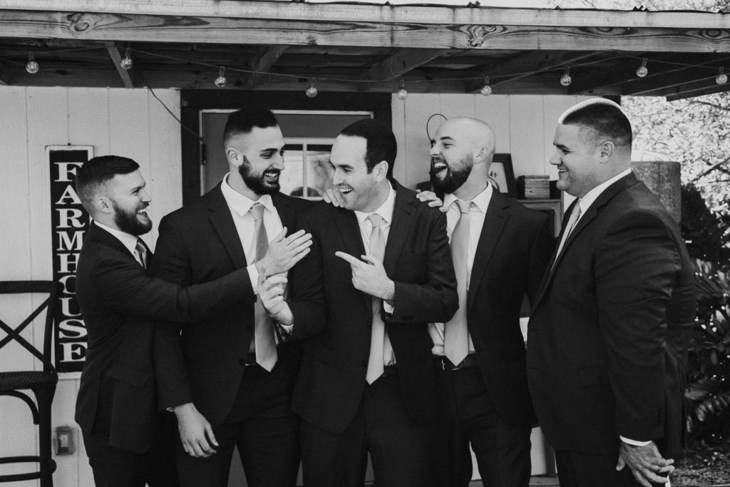 Black and white photo of groom joking with groomsmen at Cattleya Chapel FL wedding photography