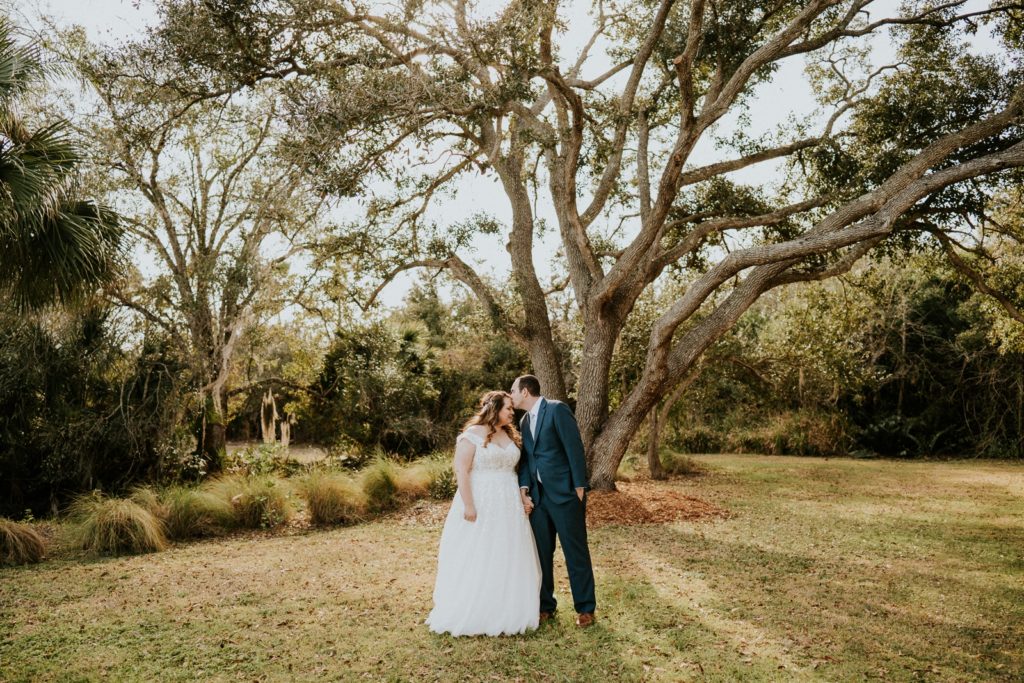 Forehead kiss under big tree rustic wedding Cattleya Chapel Vero Beach FL