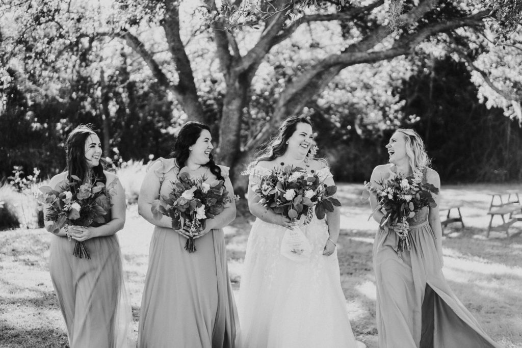 Black and white photo of bride with laughing bridesmaids