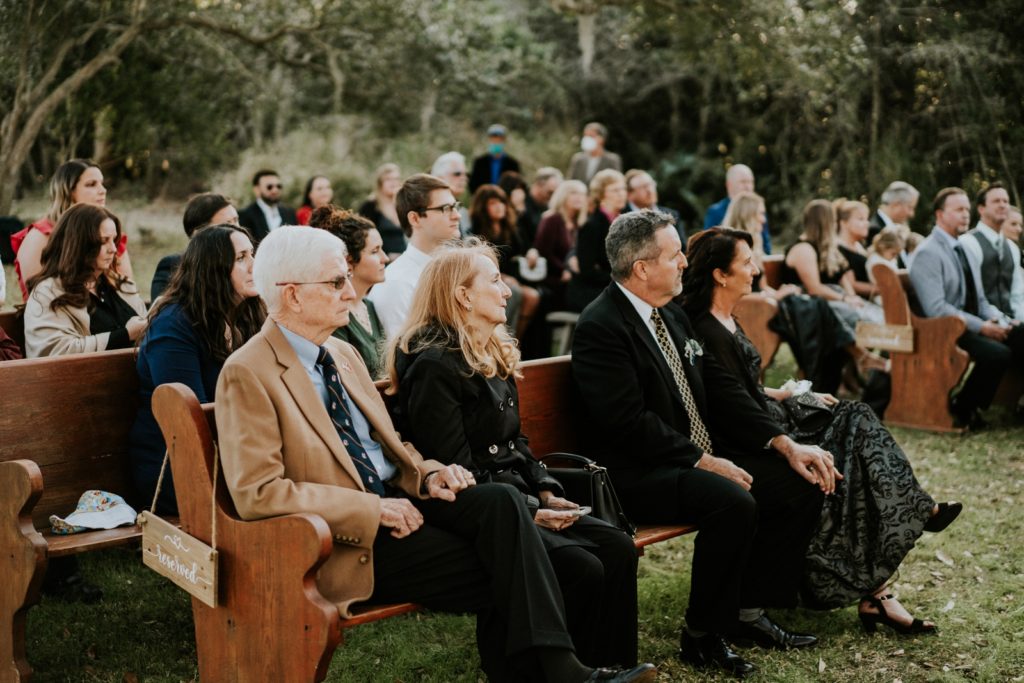 Wedding guests watch outdoor wedding ceremony