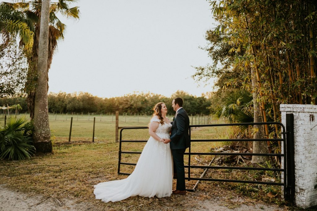 Bride and groom lean on farm fence Stuart FL wedding photography