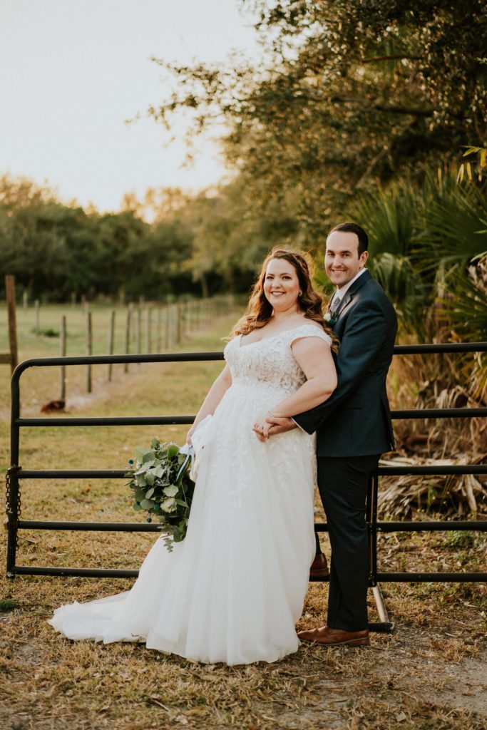 Bride and groom lean on rustic Cattleya Chapel fence Vero Beach FL wedding photography