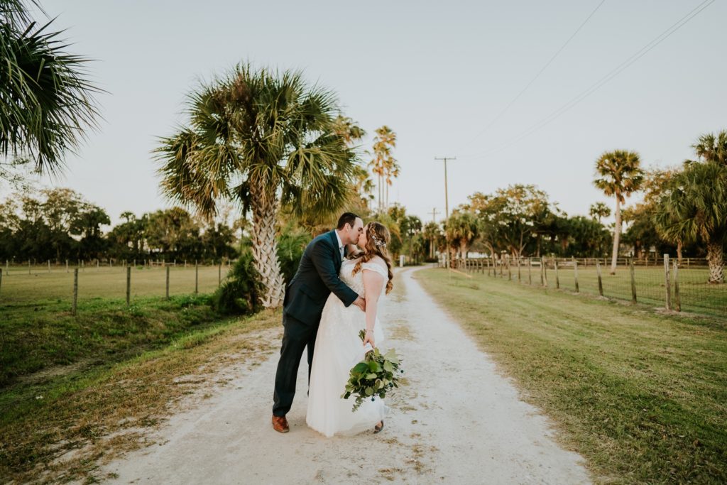Romantic kiss on dirt road with palm trees at Cattleya Chapel FL wedding