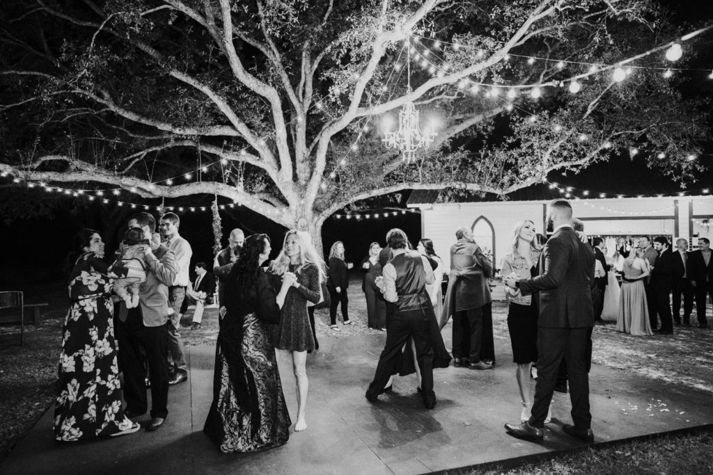 Large tree with fairy lights and chandelier over outdoor reception dance floor