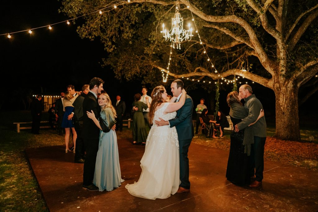 Bride and groom dance under chandelier and fairy lights at Cattleya Chapel FL wedding reception