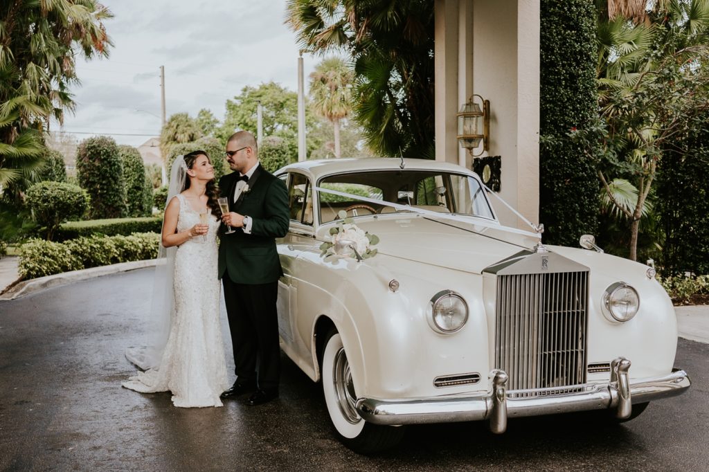 Benvenuto wedding portrait holding champagne by white Rolls Royce classic car