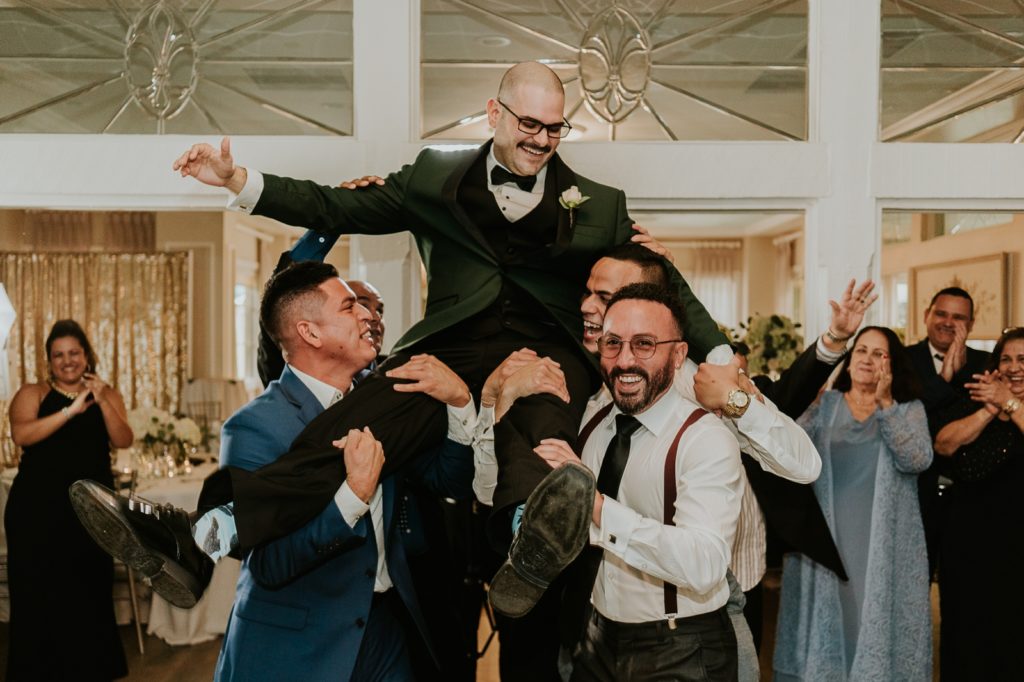 Groomsmen carry groomsmen into wedding reception